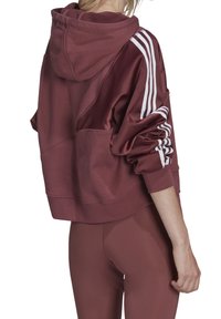 Sudadera con capucha burdeos de corte holgado, mangas de satén y detalles en raya blanca. La tela parece suave; el bolsillo tipo canguro es visible.