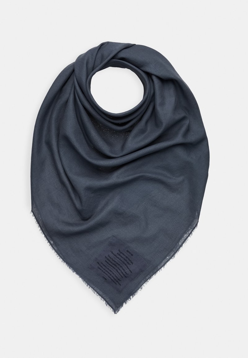 Foulard triangulaire gris foncé avec une texture douce et des bords frangés, plié en forme circulaire avec une étiquette imprimée visible près d’un coin.