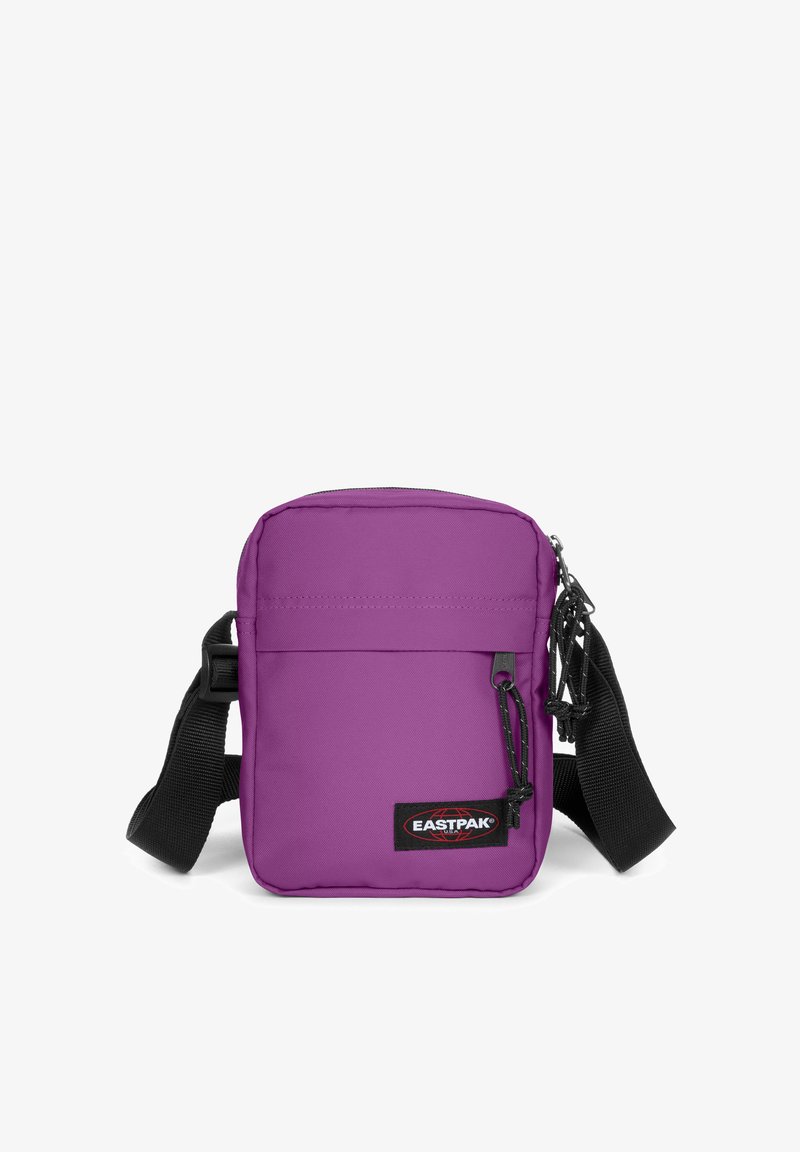 Borsa a tracolla viola con forma rettangolare, realizzata in tessuto resistente. Presenta una tasca frontale con zip, una tracolla regolabile e una patch con logo.
