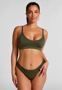 Maillot de bain bikini vert olive au design sans coutures ; le haut présente des bretelles fines ajustables et une texture douce, tandis que le bas adopte une coupe moderne taille haute.