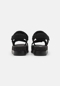 Sandalias negras con correas ajustables, plantilla texturizada y suela resistente con motas y una ligera elevación.