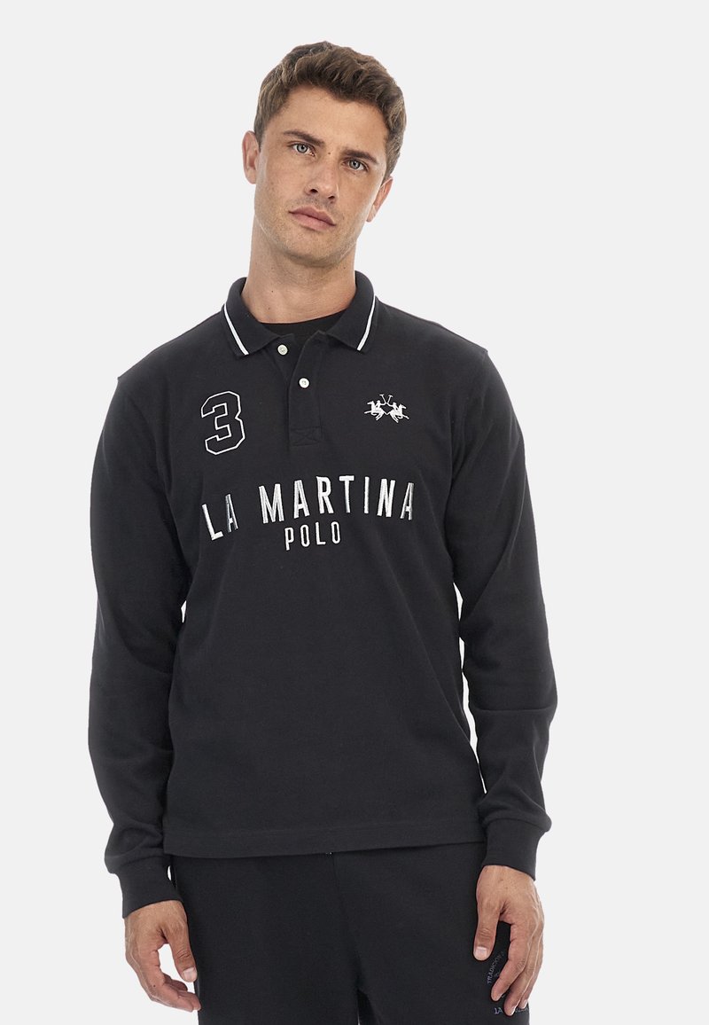 Svart långärmad polo med vita detaljer, med en "3" på bröstet, texten "LA MARTINA POLO" och en hästlogotyp ovanför.