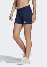 Tmavomodré športové šortky s širokým pásom, s bielym logom Adidas. Hladká, elastická tkanina s priliehavým strihom, vhodné na šport.