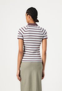 Randig polo t-shirt med ett mönster i vinröd och vitt, korta ärmar och ribbad krage; kombinerad med en enkel grön kjol.