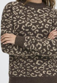 Pulover maro cu un model din imprimeu de leopard în nuanță de crem, având un guler și manșete ribbate. Textură moale, croială lejeră și mâneci lungi.