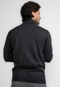 Ciemnoszary sweter z wysokim kołnierzem, długimi rękawami i prążkowanym wykończeniem. Wykonany z miękkiego materiału o gładkiej fakturze. Minimalistyczny design.