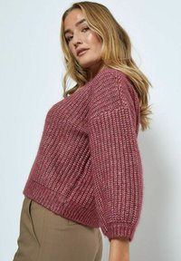 Kleines gestricktes Sweater in Mauve, mit einer strukturierten, groben Maschenart, Rundhalsausschnitt und lockeren Ärmeln, kombiniert mit hellbraunen Hosen.