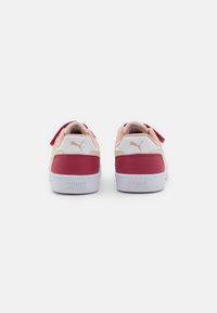 Rote und weiße Sneaker mit strukturierter Oberfläche, gepolstertem Absatz und Klettverschluss. Mit einem auffälligen Logo auf der Ferse und glatter Gummisohle.