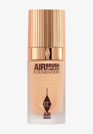 Airbrush Flawless Foundation in a clear glass bottle with a textured gold cap. Label in dark brown; features wing design and branding.