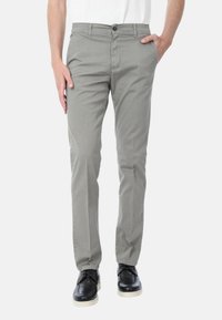 Chinos in cotone grigi con vestibilità slim, caratterizzati da una chiusura frontale con bottone, tasche laterali e una texture liscia. Abbinati a scarpe nere.
