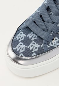 Μπλε υφασμάτινο αθλητικό παπούτσι με μεταλλικές ασημένιες λεπτομέρειες, διαθέτοντας σχέδιο με μοτίβο και επίπεδα κορδόνια. Περιλαμβάνει λευκή καουτσούκ σόλα.