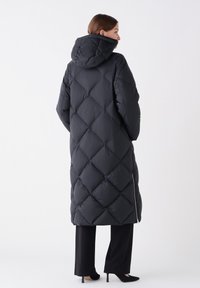 Schwarze Daunenjacke mit einem rautenförmigen Steppmuster, Kapuze und seitlichem Reißverschluss. Langer Schnitt, der bis zur Mitte der Wade reicht. Glatte, glänzende Oberfläche.