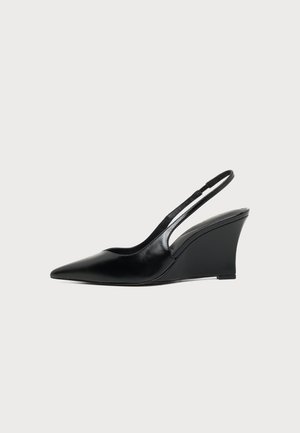 Chaussure compensée en cuir noir à bout pointu et bride arrière avec talon haut et fine sangle sur le talon, vue de profil.