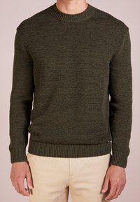 Stickad olivgrön tröja med rund halsringning, ribbade ärmslut och nederkant. Strukturerat tyg med mjukt avslut, figurnära design.