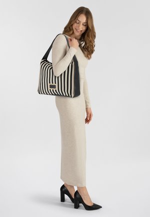 Bolso de mano a rayas en blanco y negro con una tela texturizada y detalles en cuero negro liso. Presenta una placa con el logotipo en la parte frontal.