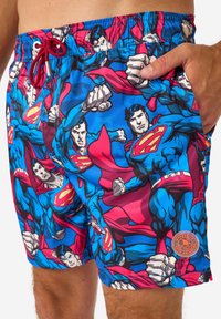 Maudymosi šortai su mėlynu fonu ir pakartotiniu stilizuotų superherojų raštu raudonai ir mėlynai, elastinga juostos juosta ir šoninės kišenės.