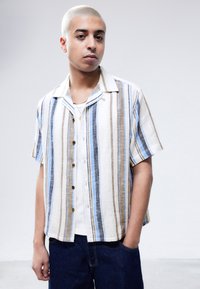 Short-sleeve button-up shirt featuring vertical stripes in blue, brown, and white, made of lightweight fabric with a relaxed fit.