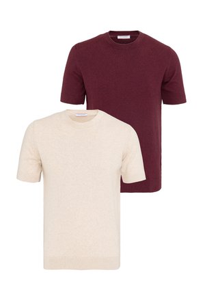 Deux pulls en maille unis à manches courtes, un crème devant et un bordeaux derrière, tous deux avec un col rond sur fond blanc.