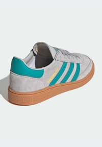 Grijze suède sneaker met teal strepen en hiel. Voorzien van een gestructureerde gumzool en gouden "Spezial" lettering op de zijkant.