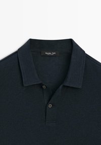 Polo bleu marine avec un col et deux boutons, affichant une étiquette Massimo Dutti à l'intérieur de l'encolure.