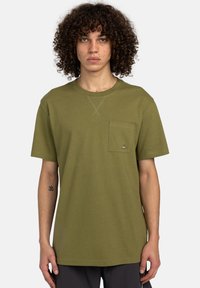 Olivengrøn bomulds t-shirt med rund hals, korte ærmer, en brystlomme og kontrasterende syninger. Løs pasform, ensartet tekstur.