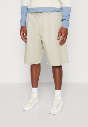 Pantalones cortos beige de corte relajado, hechos de algodón, con bolsillos laterales, detalles de pliegues y una cinturilla con cierre de botón.