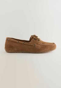 Mocassin homme en daim marron avec détails en lacets et semelle en caoutchouc, présenté en vue latérale sur un fond clair uni.