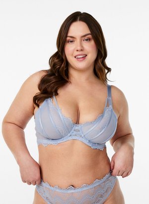 Curvy woman with long brown hair wearing light blue lace bra and matching panties, smiling against a white background.