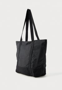 Μαύρη τσάντα tote από λείο νάιλον με διπλές υφασμάτινες λαβές, ορθογώνιο σχήμα και υφή μαύρης βάσης.