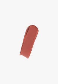 Color de labios mate en terracota cálido, difuminado en una forma alargada sobre un fondo blanco, mostrando una textura suave y cremosa.