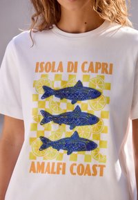 Biała bawełniana koszulka z grafiką przedstawiającą trzy ryby w odcieniach niebieskiego i zielonego, motywy cytrynowe oraz napis "ISOLA DI CAPRI AMALFI COAST."