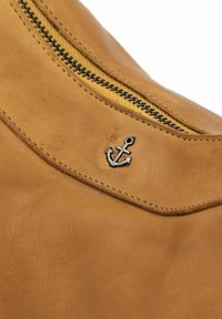 Borsa in pelle marrone con una texture liscia, caratterizzata da un emblema ad ancora argento e da una cerniera nera lungo il bordo superiore.