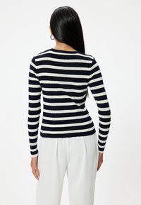 Marinblå och vit randig ribbad tröja med långa ärmar, figurnära design, rund halsringning och strukturerad finish.