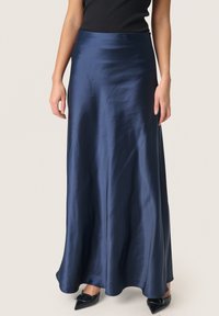 Gonna maxi in satin blu navy con una texture liscia, forma svasata e vita alta, indossata con scarpe nere con punta affusolata.