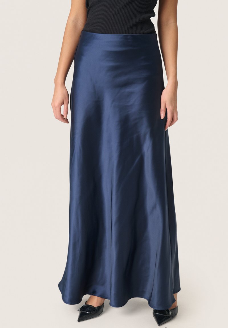 Gonna maxi in satin blu navy con una texture liscia, forma svasata e vita alta, indossata con scarpe nere con punta affusolata.