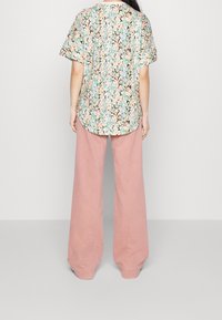 Haut à manches courtes imprimé floral avec un ourlet arrondi, assorti à un pantalon rose à jambes larges en tissu doux.