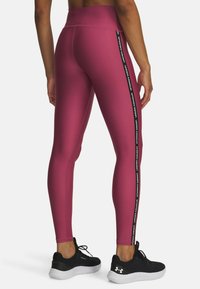 Dopasowane legginsy w głębokim odcieniu bordo z gładką fakturą, z czarnymi paskami bocznymi zawierającymi logo "Under Armour".