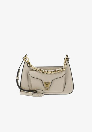 Sac à main en cuir beige avec une poignée chaîne en or, une poche avant avec un fermoir en or et une bandoulière en cuir ajustable.