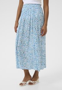Jupe maxi florale avec un fond bleu pâle, ornée de petites fleurs bleues et vertes, dotée d'une taille élastique et d'un design fluide.