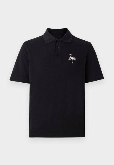 Black polo shirt made of soft cotton. Features a three-button placket and a small embroidered flamingo design with "E.A." on the chest.
