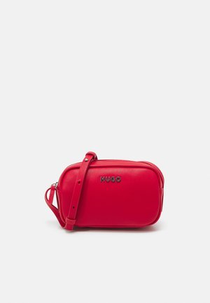 Red leather crossbody bag with adjustable strap and metal "HUGO" logo on front, displayed against plain white background.