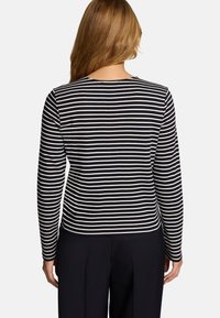 Haut ajusté à manches longues à rayures noires et blanches, avec un col rond et un tissu en coton doux. Design simple et décontracté.