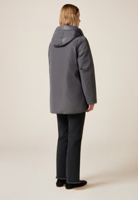 Grå isoleret jakke med hætte, der har et elegant design og elastiske manchetter. Bagsiden er ren uden synligt hardware eller pynt.