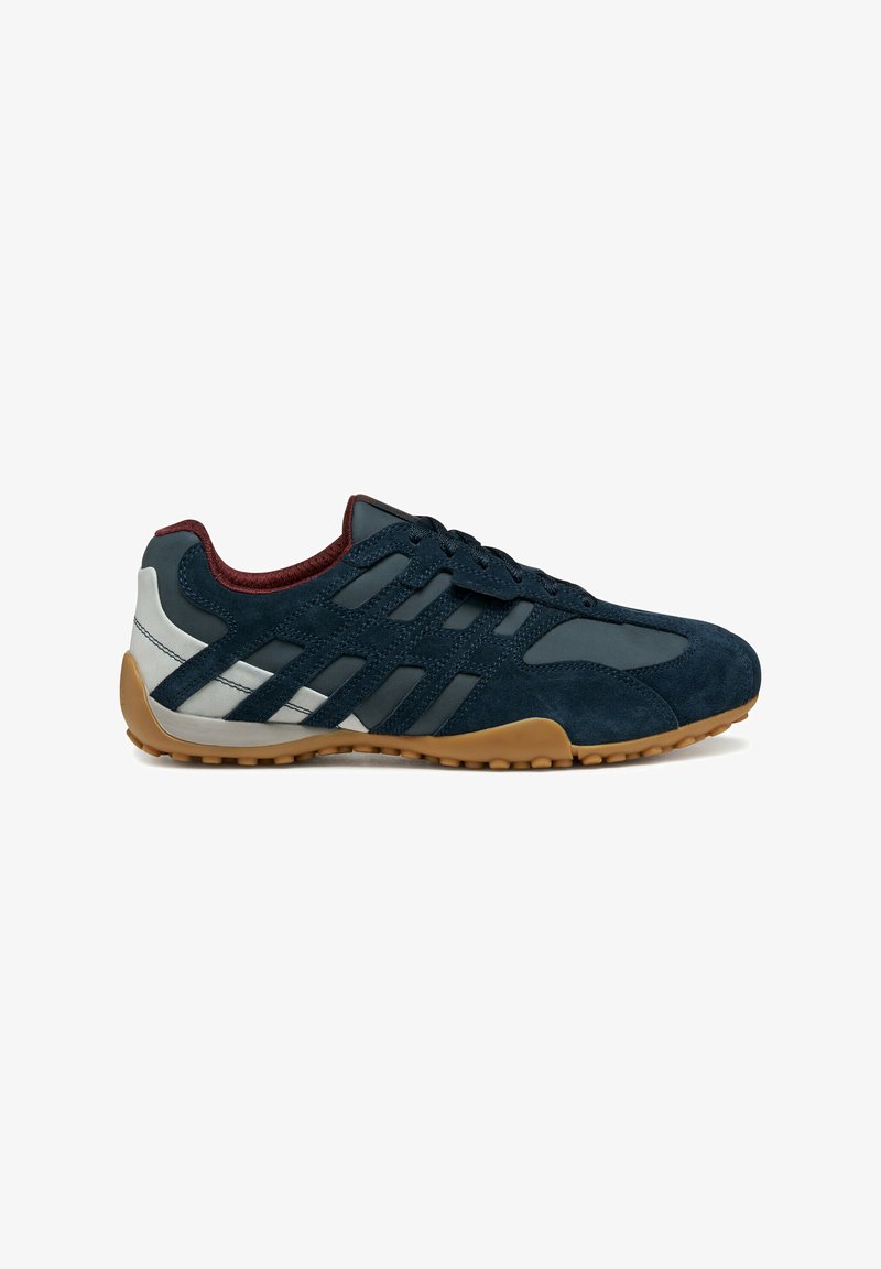 Sneaker in camoscio blu con accenti grigi, dotato di una tomaia strutturata, suola in gomma naturale e un sistema di allacciatura con strisce diagonali ai lati.