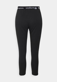 Schwarze Leggings aus dehnbarem Material, mit einem breiten elastischen Bund und dem weißen "Champion"-Logo, sowie einem figurnahen Schnitt.