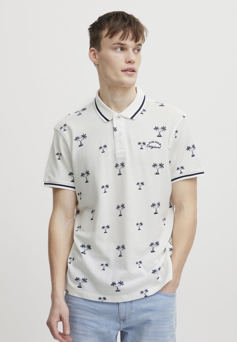 Hvit polo skjorte med marineblå palmetre mønster, ribbet krage og mansjetter, samt brodert "Original" detalj. Myk stoff, avslappet passform.
