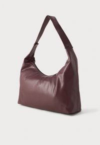 Pehmeast maroon värvi nahast õlakotist, millel on tõmblukk ja reguleeritav rihm, on kujutatud ühetaolise heledahalli tausta ees.