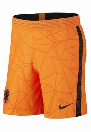 Lyse orange atletikshorts med geometriske mønstre, sort stribe på siden, sort Nike-swoosh og et sort løveemblem på venstre forben.