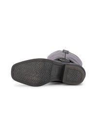 Bota de goma gris con una suela texturizada, que presenta una parte superior flexible y un acento de correa. La suela tiene un patrón en zigzag para un mejor agarre.