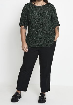 Haut à manches courtes à motif vert et noir associé à un pantalon noir et des mocassins noirs. Coupe ample avec un col rond et une texture subtile.